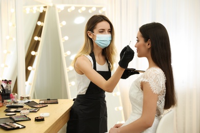 Photo of Professional makeup artist working with client in salon. Beauty services during Coronavirus quarantine