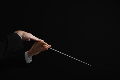 Photo of Professional conductor with baton on black background, closeup. Space for text