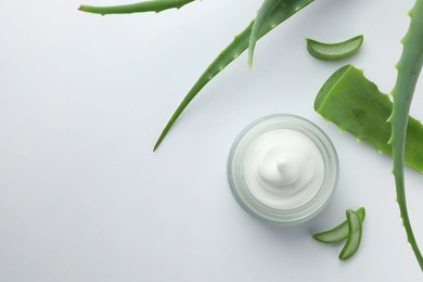 Jar of natural cream and aloe leaves on white background, flat lay. Space for text