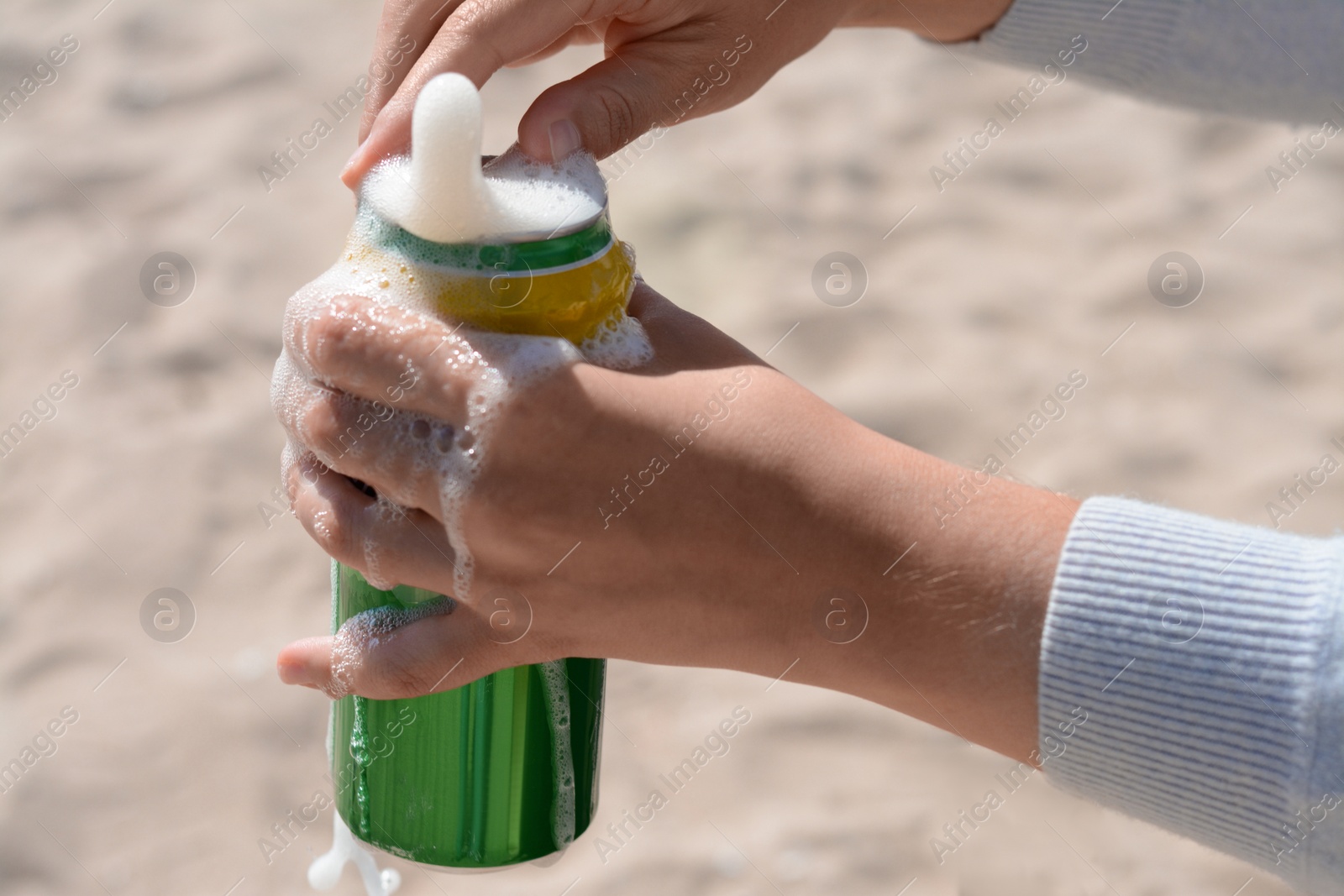 Photo of Woman opening can with sparkling drink at beach, closeup