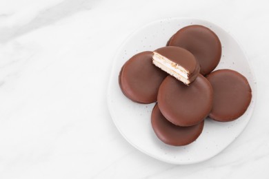 Photo of Saucer with delicious choco pies on white table, top view. space for text