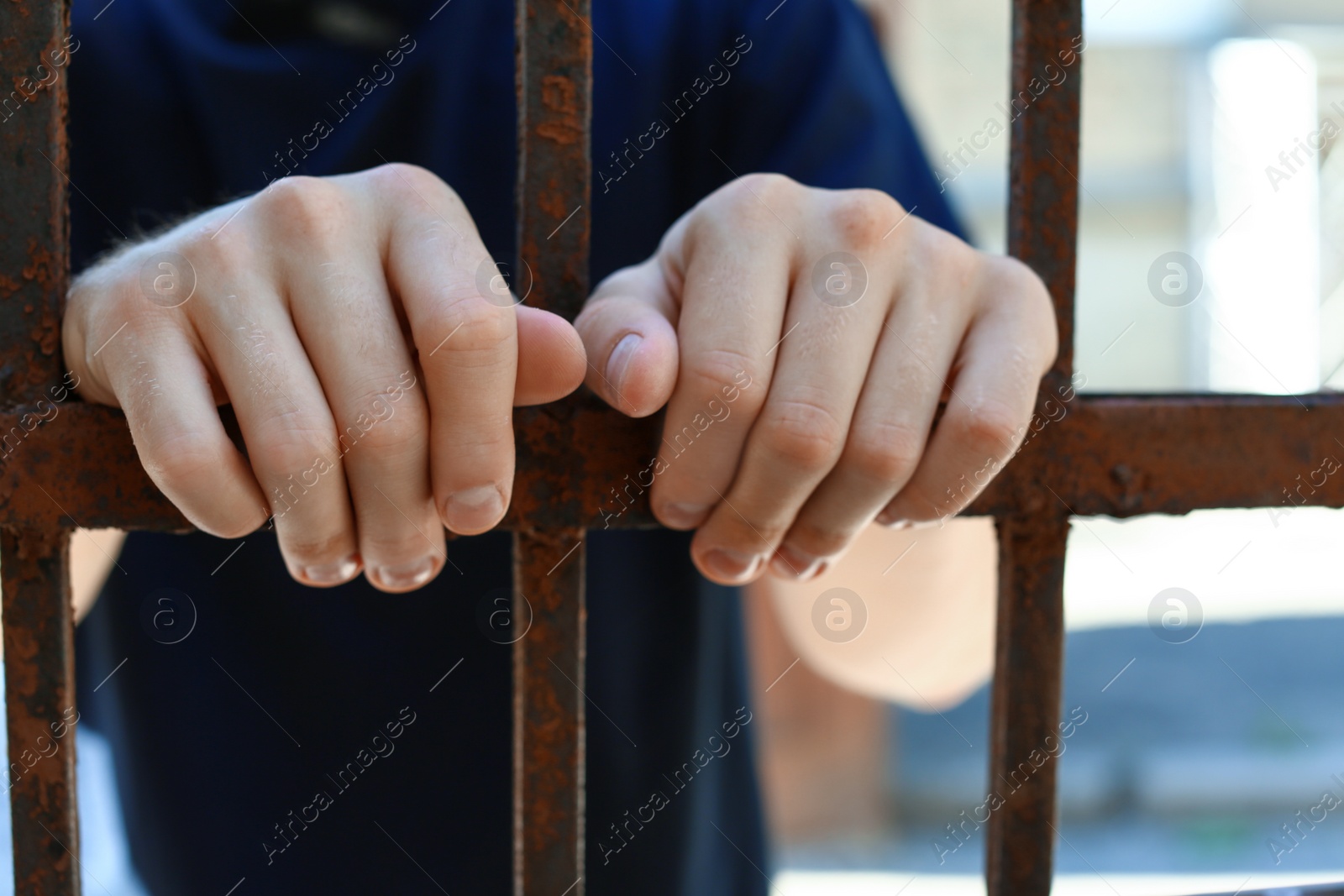 Photo of Man detained in jail outdoors, closeup. Criminal law