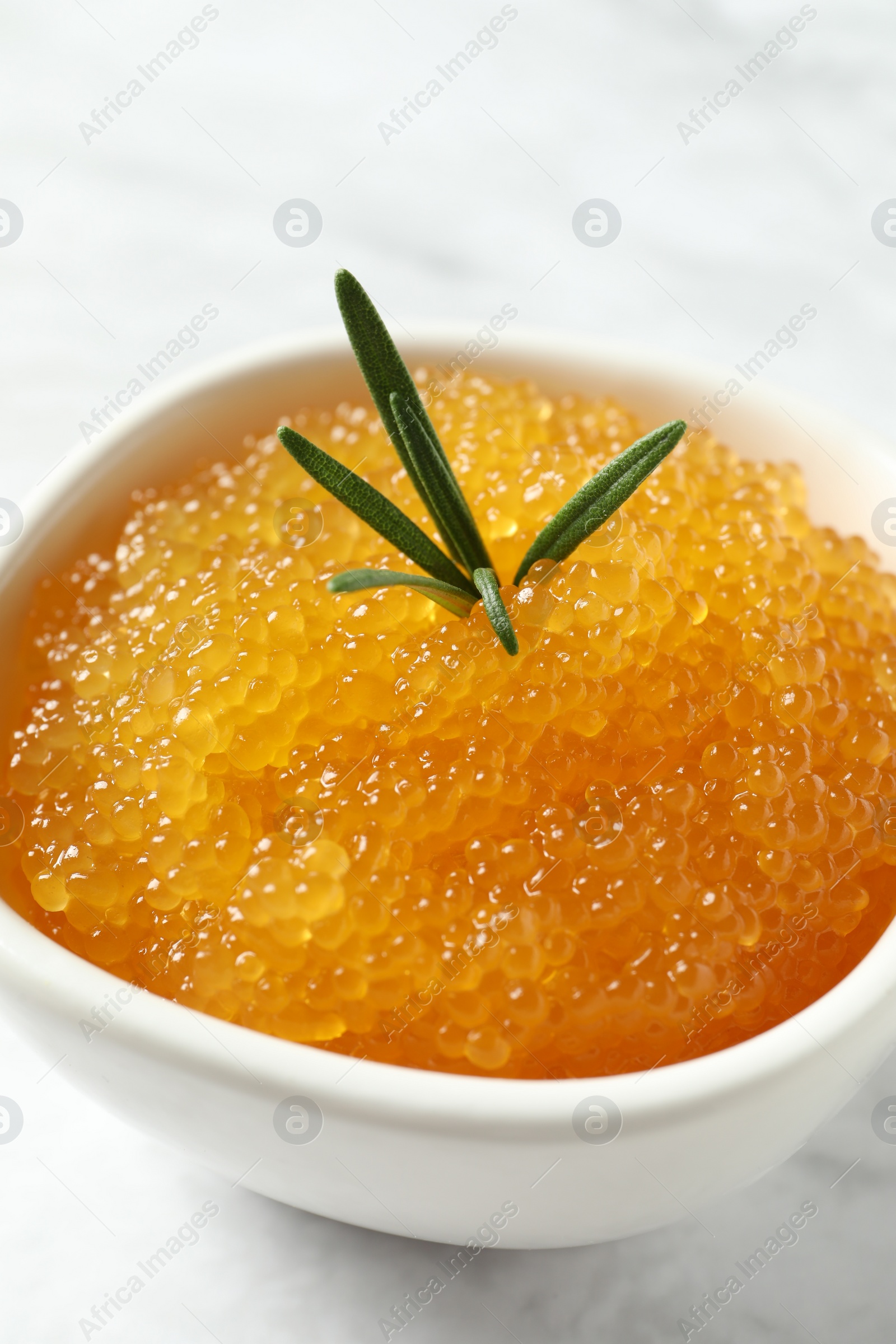 Photo of Fresh pike caviar and rosemary in bowl on white table, closeup