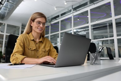 Woman working on laptop at white desk in office