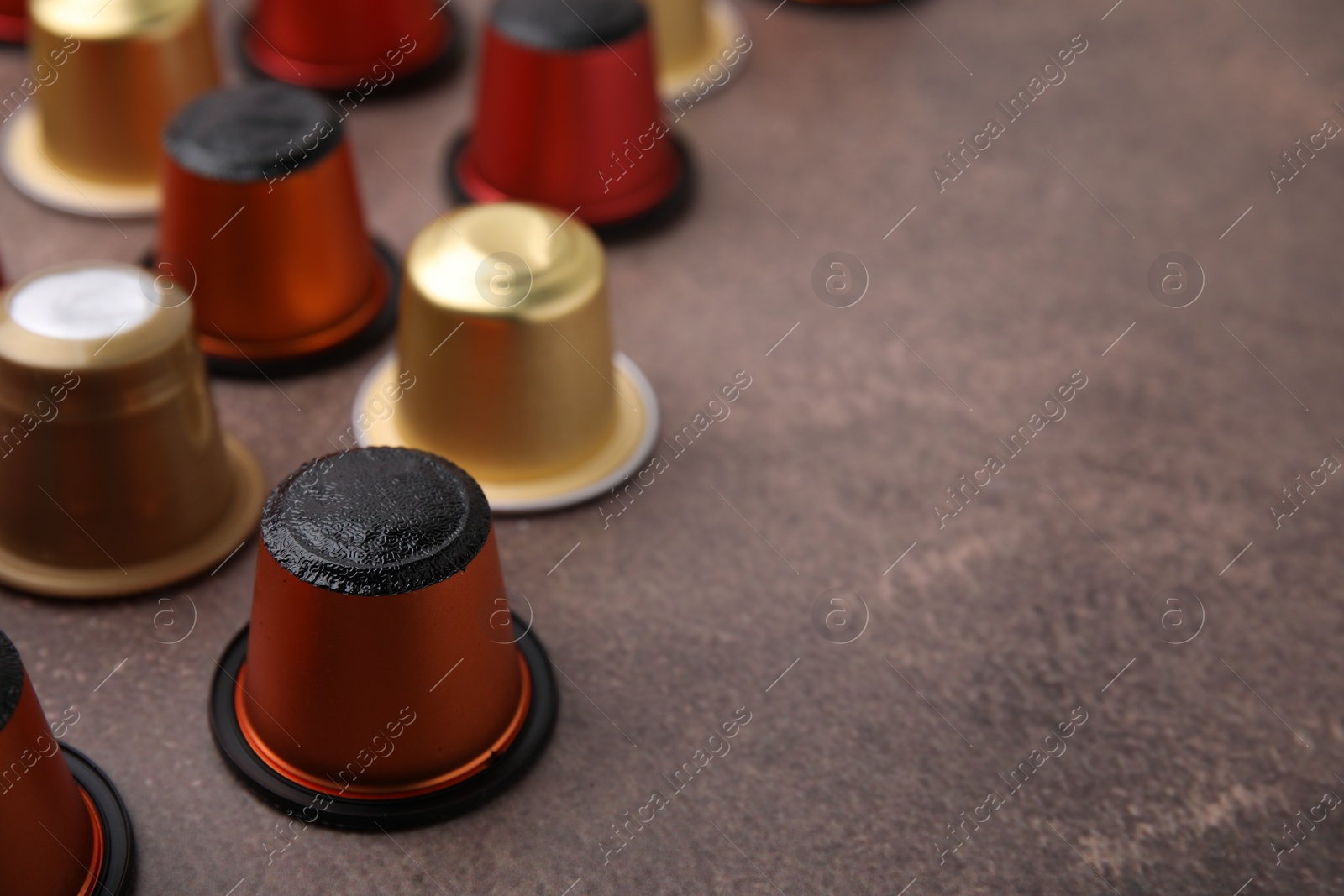 Photo of Many coffee capsules on brown table, closeup. Space for text