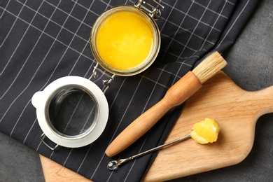 Flat lay composition with clarified butter and basting brush on grey background