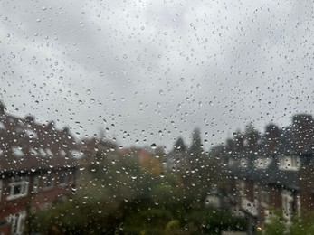 Photo of View on city street through window with water droplets on rainy day, closeup