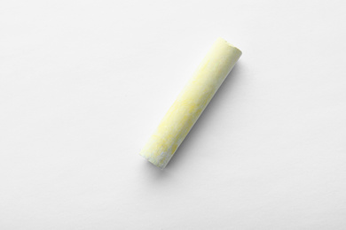 Photo of Small piece of yellow chalk isolated on white, top view