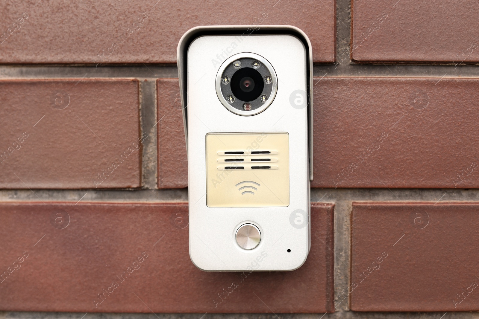 Photo of Modern intercom with camera on red brick wall