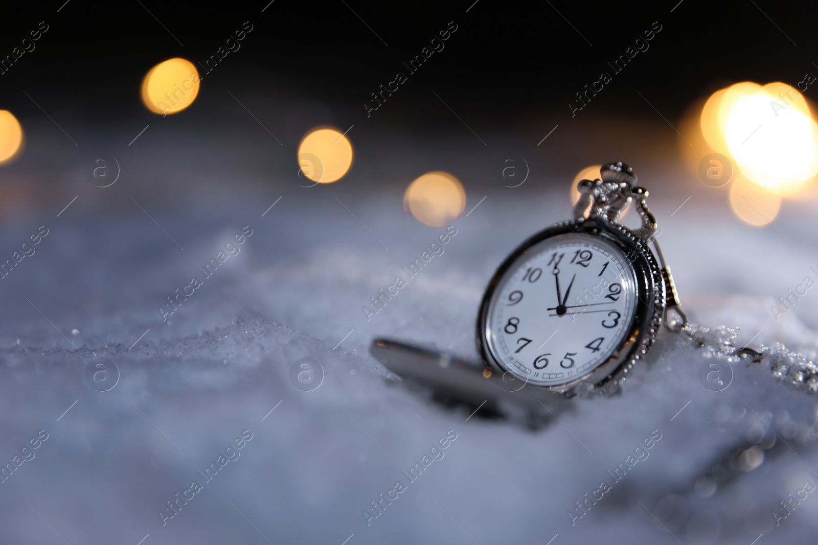 Photo of Pocket watch and Christmas lights on white snow outdoors, space for text. Midnight countdown