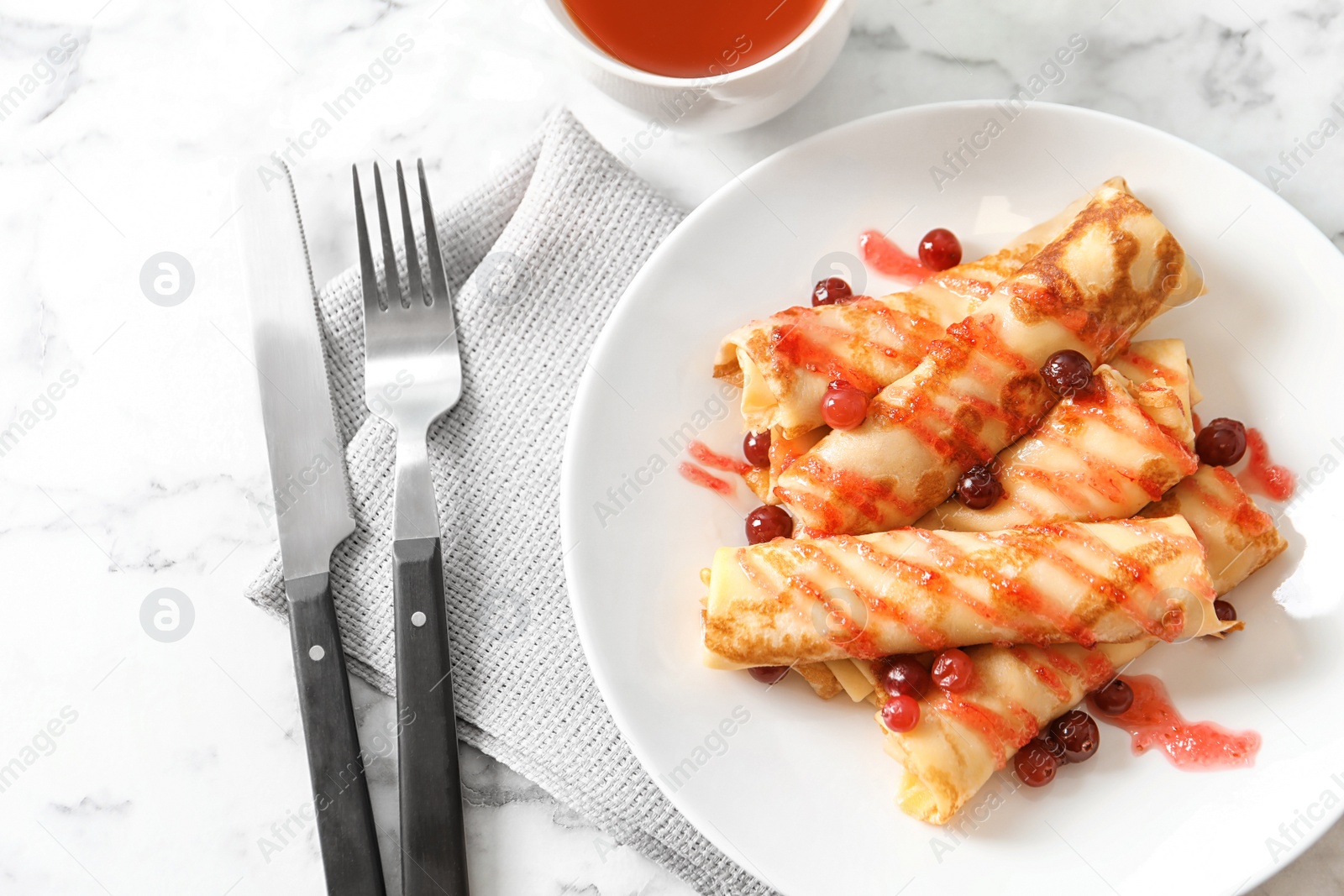 Photo of Thin pancakes with berries and syrup on plate, top view