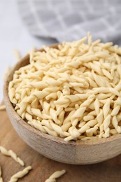 Bowl with uncooked Italian trofie pasta on table, closeup