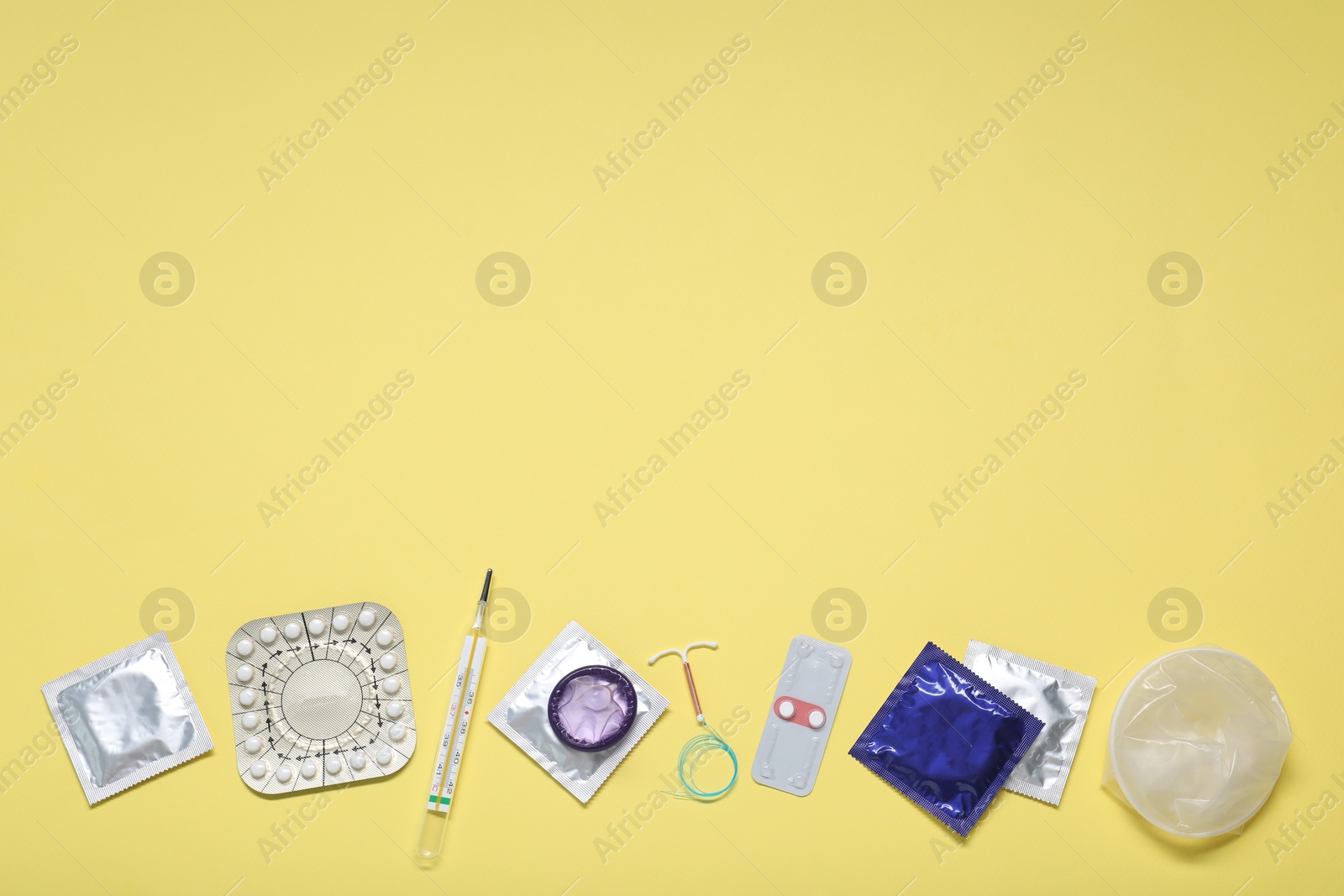 Photo of Contraceptive pills, condoms, intrauterine device and thermometer on yellow background, flat lay and space for text. Different birth control methods