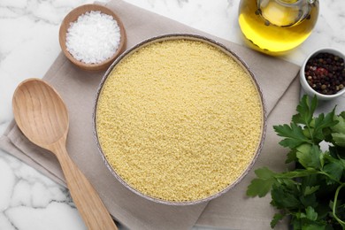 Photo of Raw couscous and ingredients on white marble table, flat lay