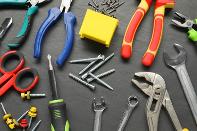Photo of Different pliers, screwdriver, wrenches and other tools for repair on black textured table, flat lay