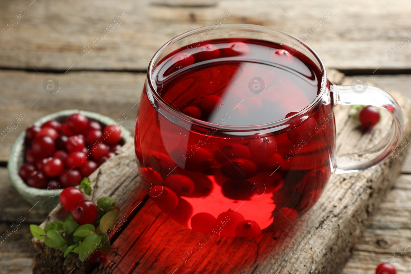 Photo of Delicious cranberry tea and berries on wooden table, closeup