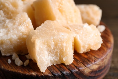 Photo of Pieces of delicious parmesan cheese on wooden board, closeup