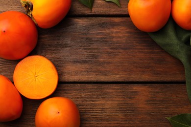 Photo of Delicious ripe persimmons on wooden table, flat lay. Space for text