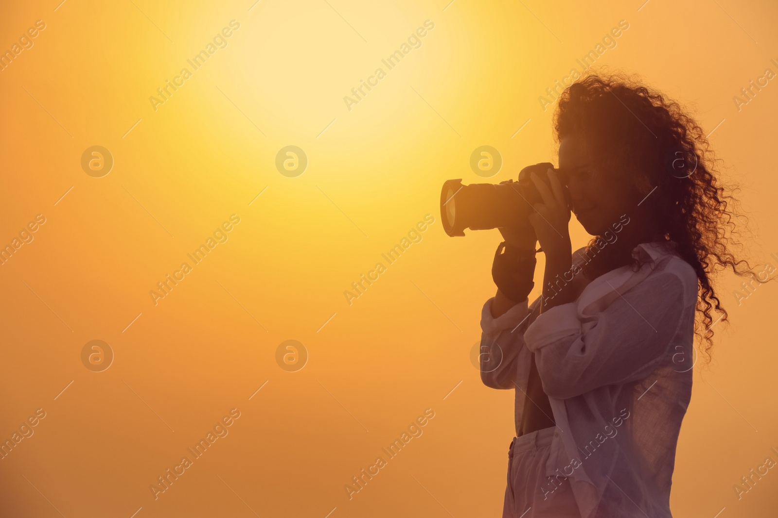 Photo of Photographer taking photo with professional camera outdoors at sunset