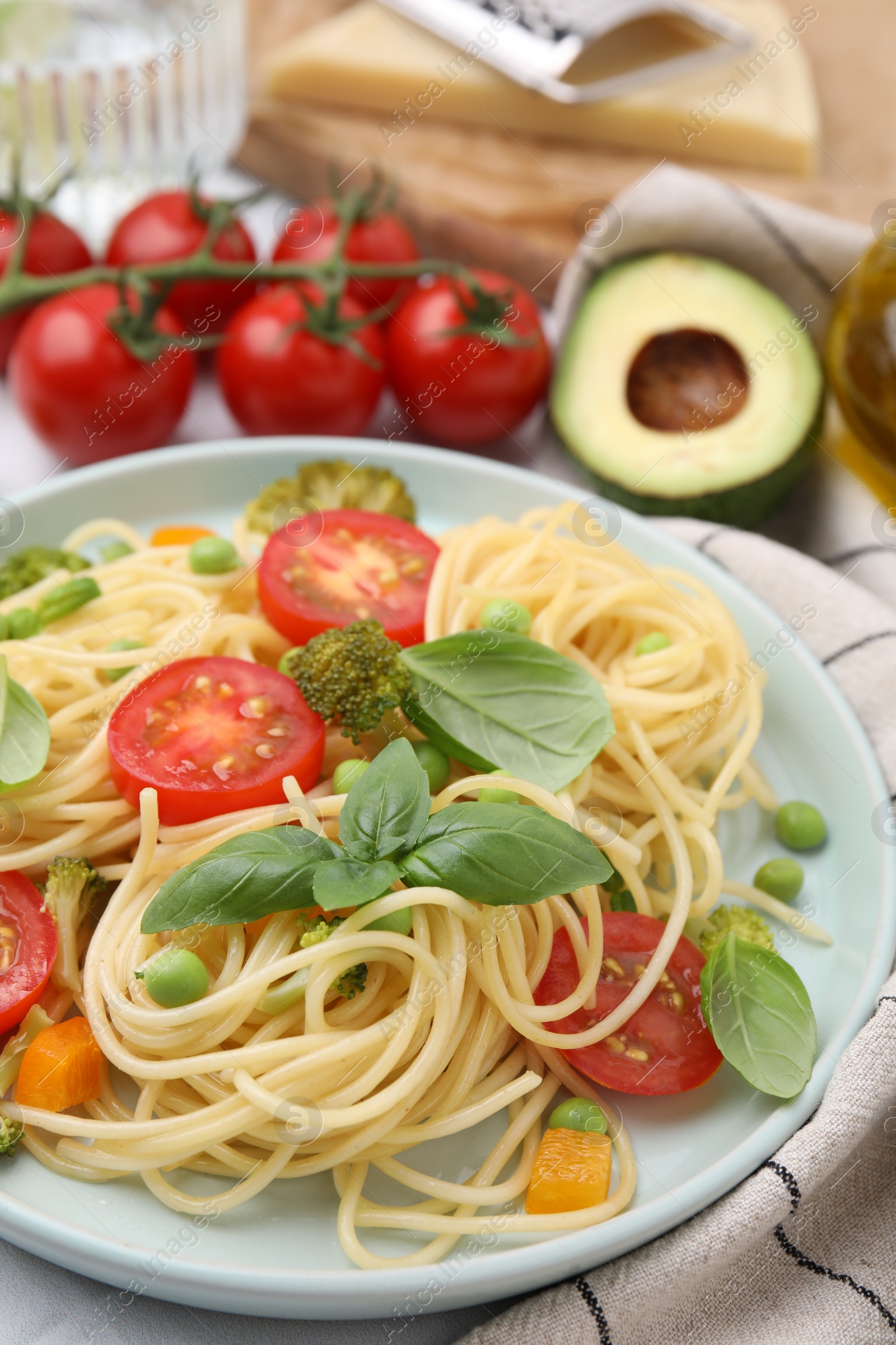 Photo of Plate of delicious pasta primavera and ingredients on table, closeup