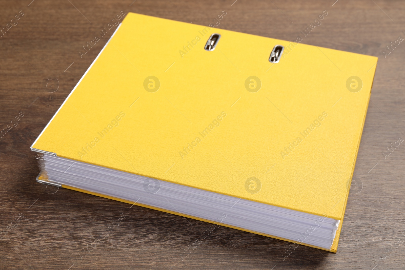 Photo of Yellow hardcover office folder on wooden table, closeup