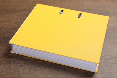 Photo of Yellow hardcover office folder on wooden table, closeup