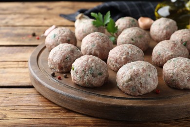 Many fresh raw meatballs on wooden table