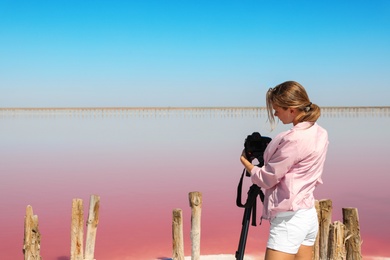 Professional photographer taking photo of pink lake on sunny day