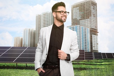 Young businessman near solar panels and beautiful view of cityscape. Alternative energy source