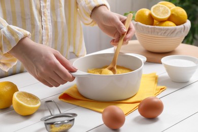 Woman cooking lemon curd at white wooden table, closeup