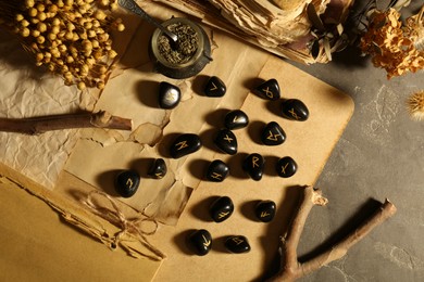 Photo of Many black rune stones, dried flowers and old books on grey table, flat lay