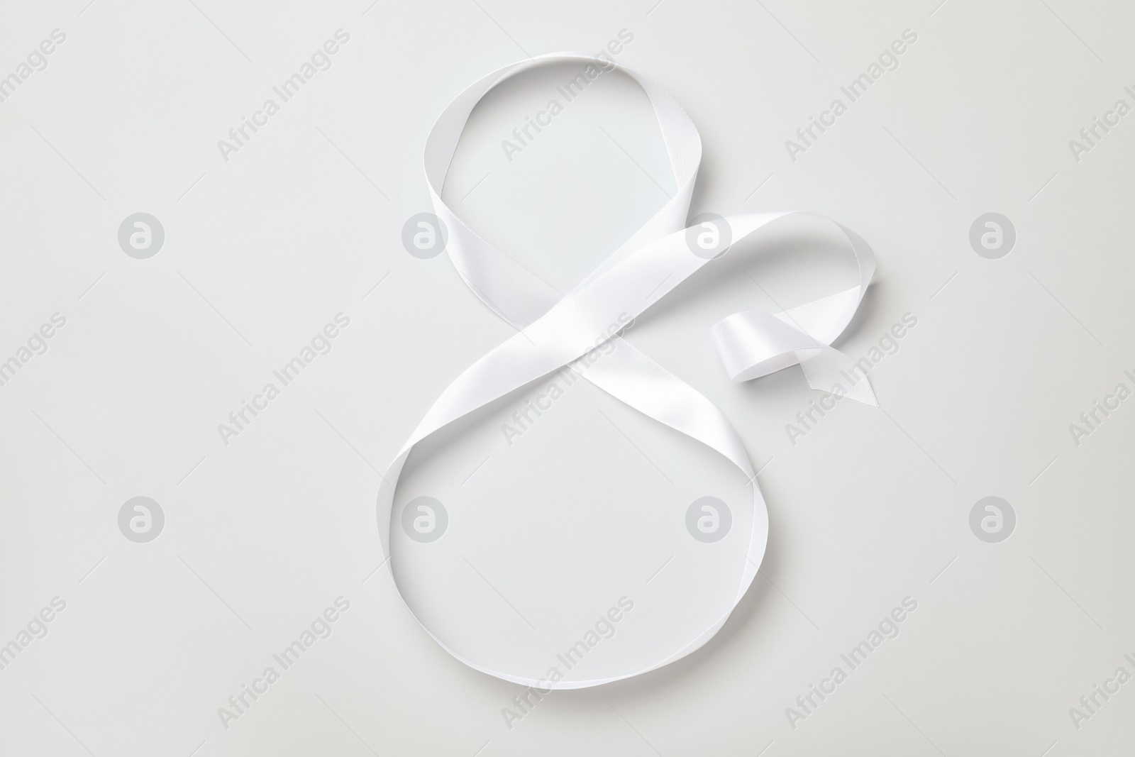 Photo of Number 8 made of white ribbon on light grey background, top view. International Women's day