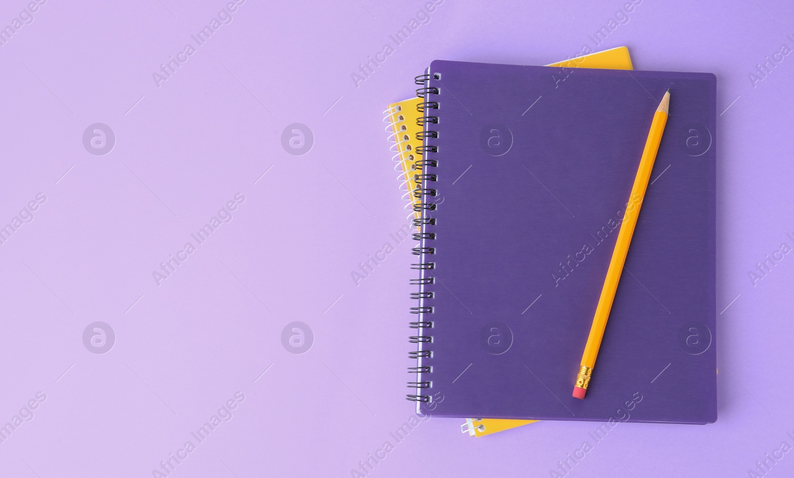 Photo of Notebooks with pencil on lilac background, top view. Space for text