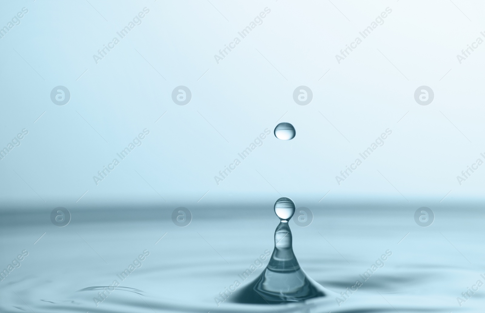 Photo of Splash of clear water with drop on light grey background, closeup