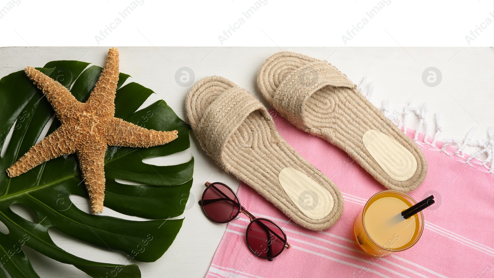 Photo of Beach accessories and drink on white wooden table, flat lay