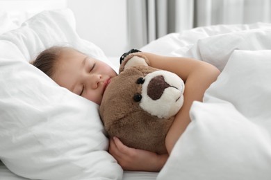 Photo of Cute little girl sleeping with teddy bear in bed