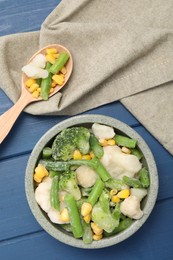 Photo of Mix of different frozen vegetables in bowl on blue wooden table, top view