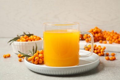 Photo of Delicious sea buckthorn tea and fresh berries on light grey table