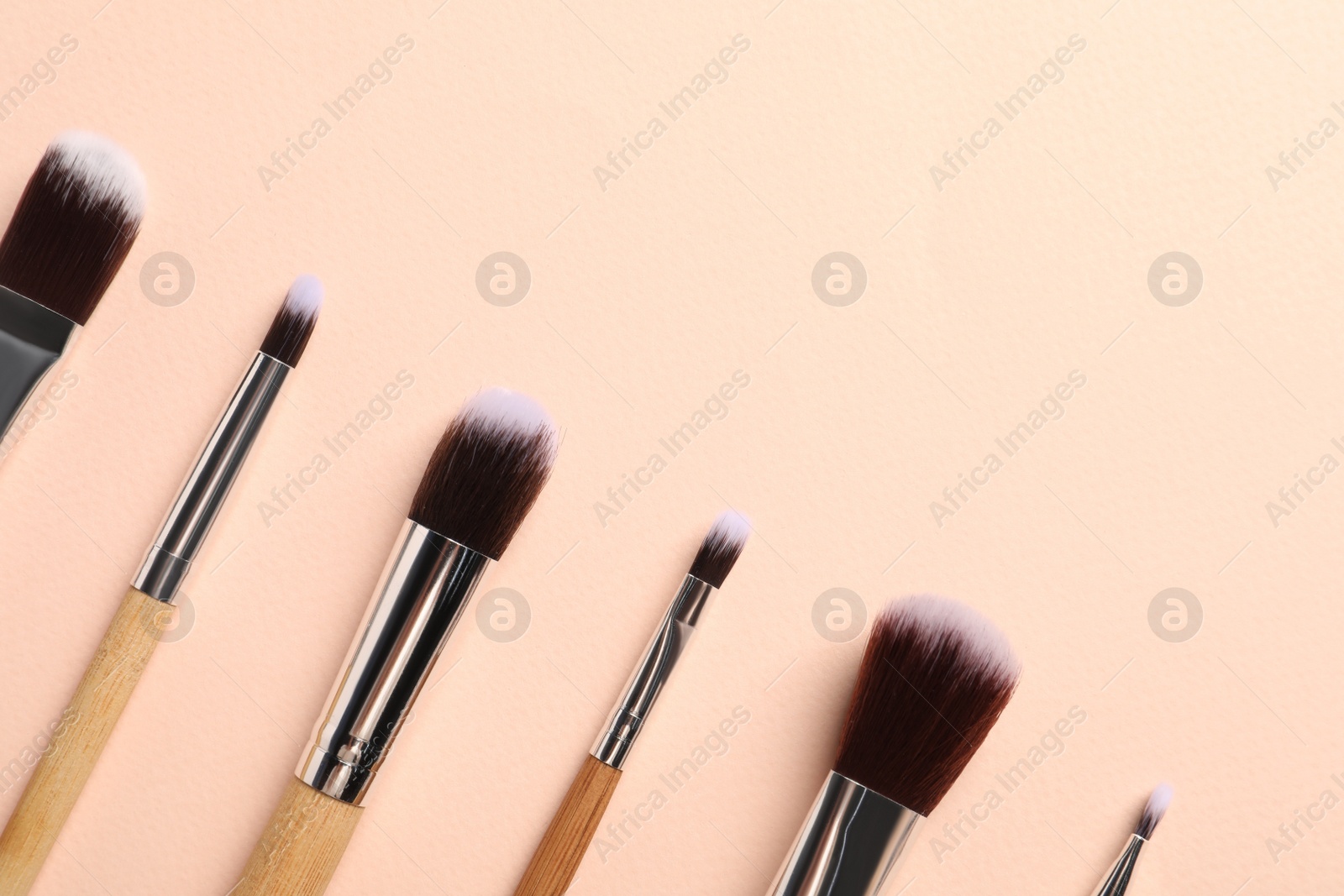 Photo of Set of makeup brushes on beige background, flat lay. Space for text