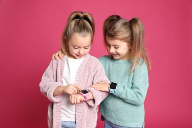 Little girls with smart watches on pink background
