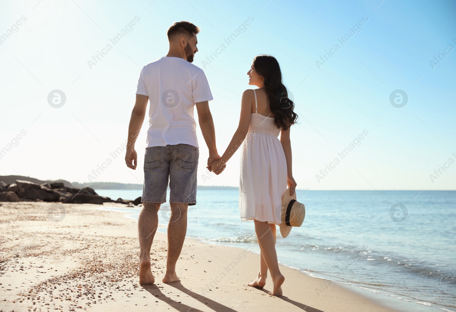 Photo of Happy young couple walking on beach near sea. Honeymoon trip