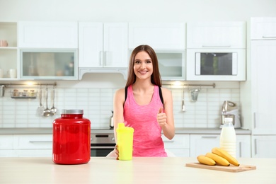 Photo of Young woman with bottle of protein shake in kitchen