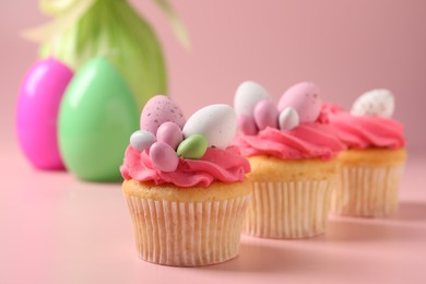 Photo of Tasty decorated Easter cupcakes on pink background, selective focus