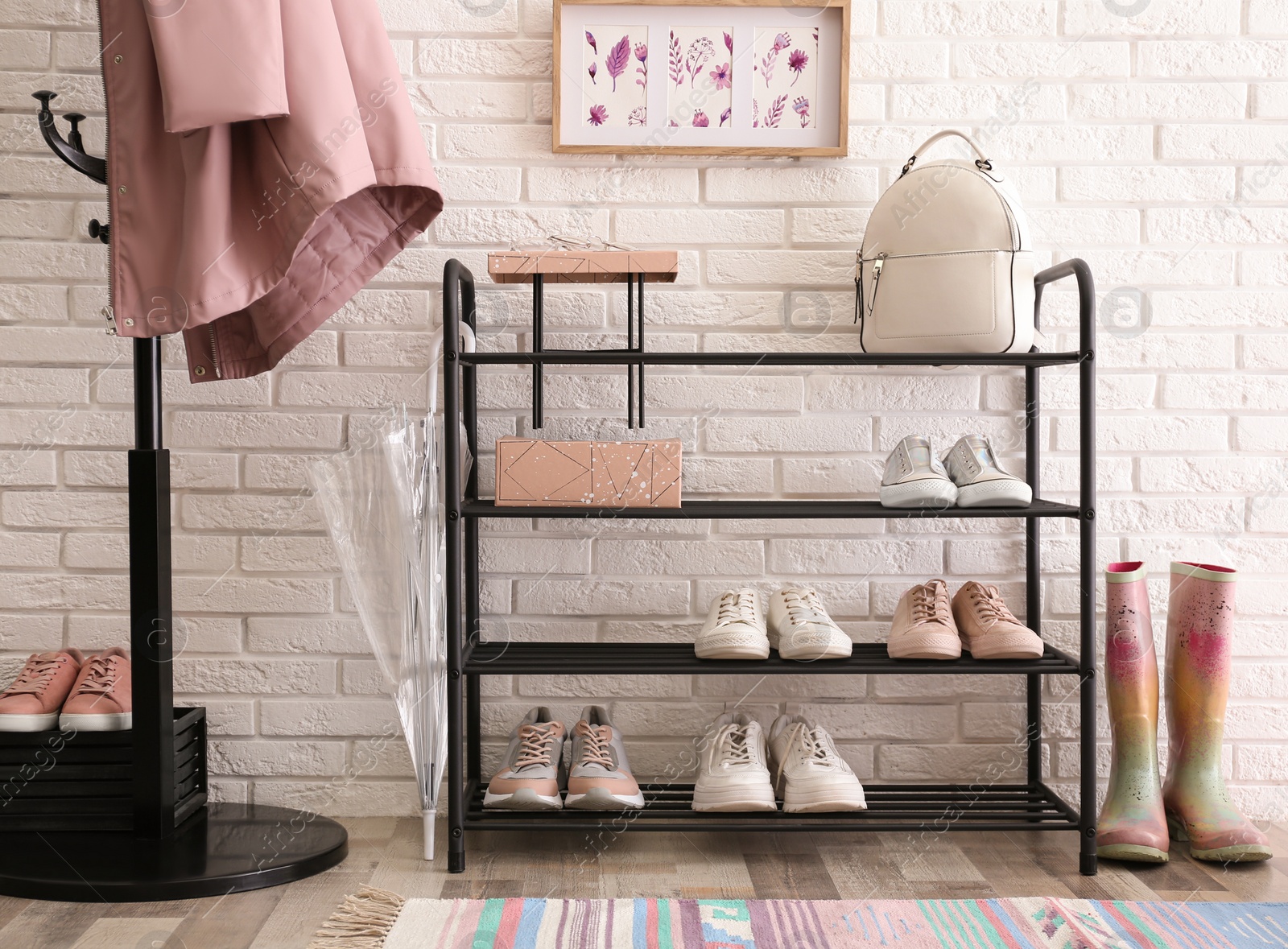 Photo of Shelving rack with stylish women's shoes and accessories near white brick wall indoors