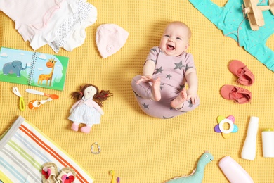 Cute little baby with clothing and accessories on color blanket, top view