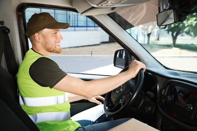 Photo of Young male courier in delivery van outdoors