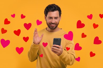 Image of Long distance love. Man video chatting with sweetheart via smartphone on golden background. Hearts flying out of device