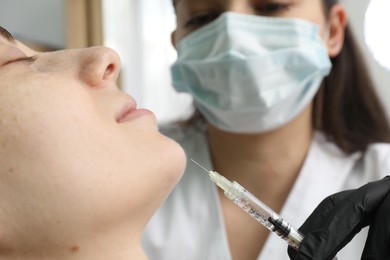 Cosmetologist giving facial injection to patient in clinic, selective focus. Cosmetic surgery