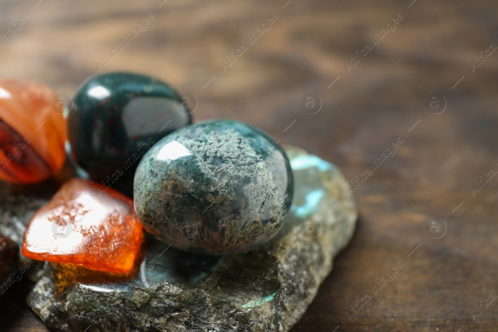 Photo of Different beautiful gemstones on wooden table, closeup