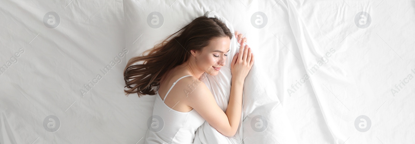 Image of Young woman sleeping on comfortable pillow in bed at home, top view. Banner design